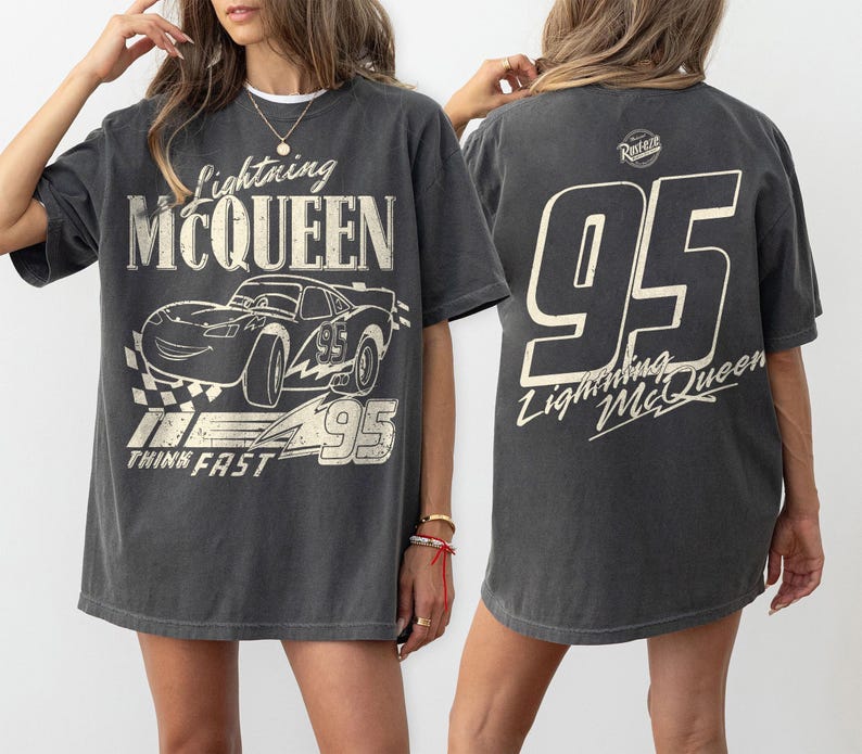 May include: Dark gray Lightning McQueen graphic t-shirt. The front features a stylized image of the race car with the text "Lightning McQueen", "95", and "Think Fast". The back of the shirt displays a large "95" and "Lightning McQueen" text.