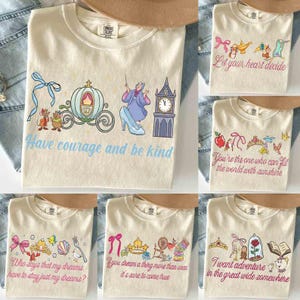 Peut inclure: T-shirts cr&egrave;me avec des graphiques et des citations sur le th&egrave;me des contes de f&eacute;es. Les motifs comprennent un carrosse, une horloge et des personnages avec le texte "Ayez du courage et soyez gentil". D'autres chemises pr&eacute;sentent des couronnes, des n&oelig;uds et les phrases "Laissez votre c&oelig;ur d&eacute;cider" et "Vous &ecirc;tes celui qui peut remplir le monde de soleil."