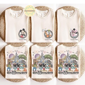 May include: Cream-coloured t-shirts featuring Disney characters and the text "Walt Disney World." The shirts display Mickey Mouse, Goofy, and Minnie Mouse designs, along with a custom name option. The shirts are arranged on a woven surface.