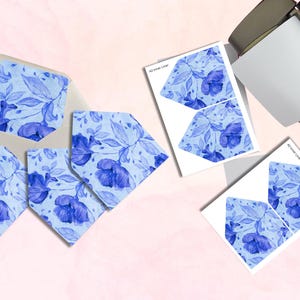 May include: Stationery set featuring blue floral designs. Includes envelopes, cards, and printed inserts. The cards and inserts have a watercolor floral pattern. The envelopes are light blue. The text "A2 Inner Liner" is visible on the inserts.