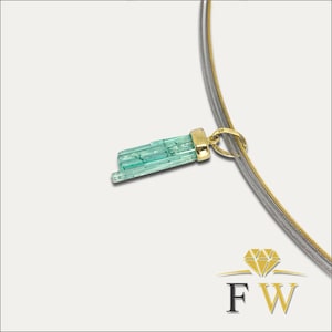May include: A necklace featuring a gold pendant with a light green, rectangular gemstone. The pendant hangs from a silver and gold-colored chain. The gemstone is a light green color with visible striations. The necklace is displayed against a white background.