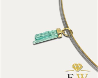 May include: A necklace featuring a gold pendant with a light green, rectangular gemstone. The pendant hangs from a silver and gold-colored chain. The gemstone is a light green color with visible striations. The necklace is displayed against a white background.