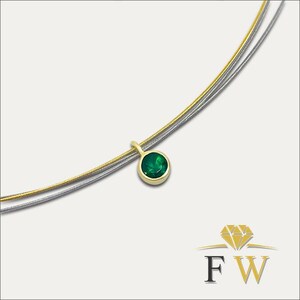May include: A necklace featuring a round, bezel-set green gemstone pendant suspended from a dual-strand chain. The chain consists of one gold-toned wire and one silver-toned wire. A logo with a diamond icon and the letters FW is visible.