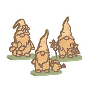 May include: Three wooden gnome figurines with light brown bodies and hats, each with a different design. One gnome holds a watering can, another has a flower on its hat, and the third holds flowers. All are on green bases.