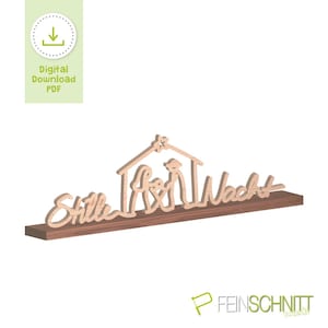 May include: A wooden nativity scene with the words "Stille Nacht" cut out. The scene includes a house, figures, and a star. The piece is mounted on a dark brown shelf. A digital download PDF icon is in the upper left corner.