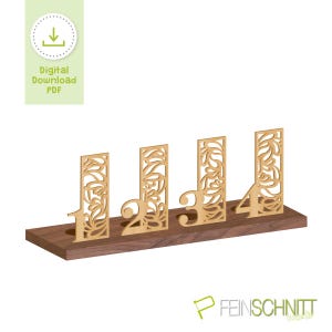 Könnte beinhalten: Holztischzahlen 1 bis 4, mit einem dekorativen Blumendesign, das in die Oberfläche der Zahl geschnitten ist. Die Zahlen sind goldfarben und stehen auf einer dunkelbraunen Holzbasis. Das Bild enthält auch den Text "Digital Download PDF".