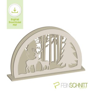 May include: A light beige, laser-cut wooden decoration featuring a forest scene with deer and trees. The design is in an arched frame, with the words "Digital Download PDF" in a green box in the upper left corner.