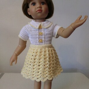 Peut inclure: Une poupée portant une robe blanche en crochet avec des accents jaunes et une jupe en crochet jaune.