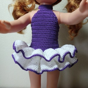 May include: Purple crochet halter top with a white crocheted ruffle skirt. The outfit is designed for a doll.