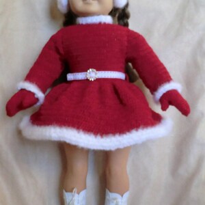 May include: A red and white doll dress with a white fur trim, a white belt with a rhinestone buckle, and white ice skates. The doll is wearing a white headband with white earmuffs.