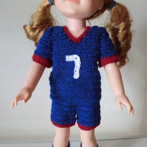 May include: A blue and red crocheted soccer jersey with the number 7 on the front. The jersey is made for a doll.