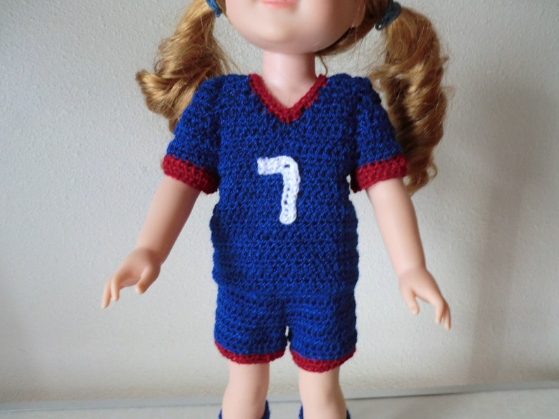 May include: A blue and red crocheted soccer jersey with the number 7 on the front. The jersey is made for a doll.