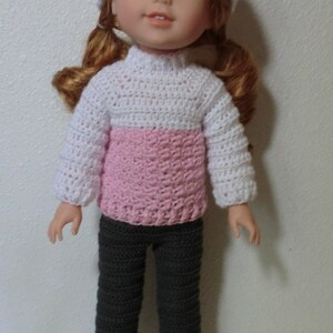 May include: A doll wearing a pink and white crocheted hat, a pink and white crocheted sweater, gray crocheted pants, and white crocheted socks.