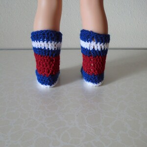 May include: A pair of red, white, and blue crocheted socks. The socks are made with a simple stitch pattern and have a white cuff.