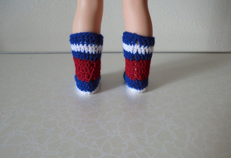 May include: A pair of red, white, and blue crocheted socks. The socks are made with a simple stitch pattern and have a white cuff.