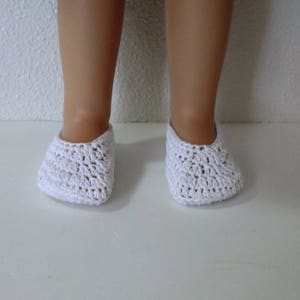 May include: White crocheted doll shoes. The shoes are made with a delicate, open-stitch pattern.