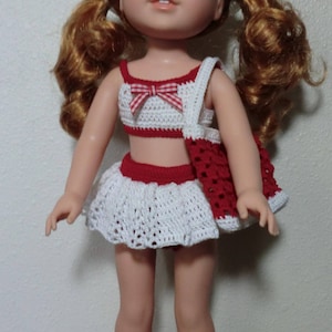 May include: A red and white crocheted swimsuit with a matching red crocheted bag. The doll is wearing a white crocheted hat with a red flower.