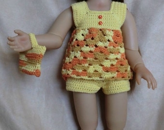 May include: A doll wearing a yellow and orange crocheted dress and hat with matching shoes. The doll has brown hair and blue eyes.