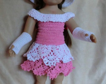 May include: A doll wearing a pink and white crocheted dress with a white crocheted hat and matching wristlets. The doll has brown hair and blue eyes.