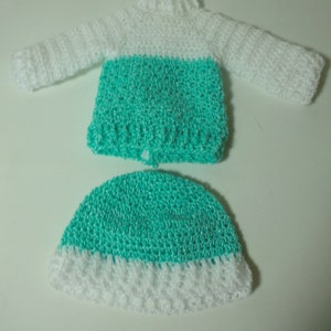 May include: A crocheted outfit for a doll, featuring a white and turquoise sweater and a matching hat.