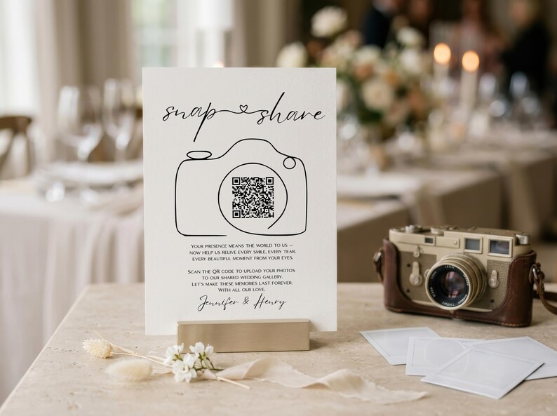 May include: A white rectangular wedding sign featuring the black text snap share, a line-art camera illustration with a central QR code, and the names Jennifer & Henry. The sign includes instructions to scan the code to upload photos.