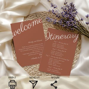 May include: Two terracotta-colored wedding cards with white script. One says "welcome" and the other "Itinerary." The welcome card includes a message to guests. The itinerary card lists the schedule for the wedding. Lavender sprigs are in the background.