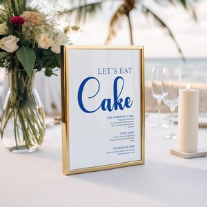 May include: A gold-framed sign with the words "LET'S EAT Cake" in blue script. The sign lists cake flavors and other desserts. A lit candle and a vase of flowers are on the white tablecloth. The scene is set outdoors.
