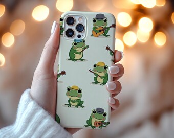 May include: A light green phone case featuring cartoon frogs playing guitars. The frogs are green with yellow and gray hats. The phone case has a light green background and a camera cutout.