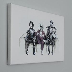 Op de afbeelding: Canvas print met Edward Scissorhands, Beetlejuice en Jack Skellington op een bank. Het kunstwerk gebruikt zwart, wit en grijstinten, met vleugjes kleur in hun kleding.