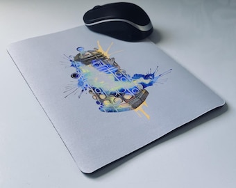 May include: A light gray mousepad featuring a watercolor-style image of a Dalek from Doctor Who, with blue, yellow, and white accents. A black wireless mouse sits on the mousepad.