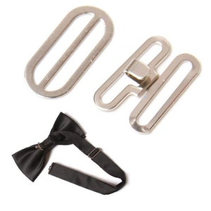 May include: A black satin bow tie with an adjustable strap, along with two silver-colored metal hardware pieces. The hardware includes a slider and a hook-and-eye closure, likely for adjusting the bow tie's fit.