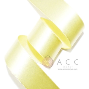 May include: A close-up of a pale yellow satin ribbon, curled in a spiral. The ribbon has a smooth, shiny surface and a subtle sheen. The text "ACC SECRET" and a website address are visible in the lower right corner.