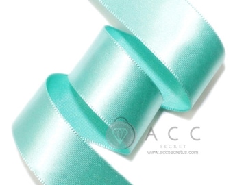 May include: A roll of satin ribbon in a light turquoise color. The ribbon is tightly wound, showcasing its smooth texture and sheen. The edges are neatly finished. The text "ACC SECRET" and website address are visible.