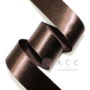 May include: Close-up of a spool of brown satin ribbon. The ribbon is curled and has a shiny, smooth texture. The text "ACC SECRET" and the website address are visible in the lower right corner.