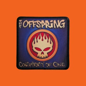 Può includere: Toppa quadrata con il nome della band "The Offspring" in testo bianco sopra un disegno di teschio con fiamme, su sfondo blu. Il testo "Conspiracy of One" è sotto. La toppa ha un bordo nero.