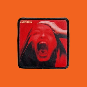 May include: A square patch featuring a red image of a person screaming, with a hand on their head. The patch has a black border and the word "SCORPIONS" is printed at the top. Set against an orange background.