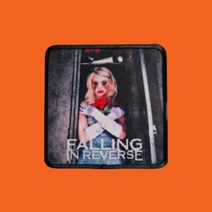 May include: A square patch with an image of a woman with blonde hair, holding red roses, and wearing white gloves. The text "FALLING IN REVERSE" is printed in white. The background is a blurred image of a doorway.