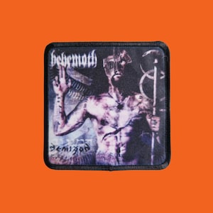 May include: Square patch with a black border featuring a detailed illustration of a figure with a staff. The figure is shirtless with a mask and holding a staff. The word "behemoth" is at the top, and "demigod" is at the bottom.
