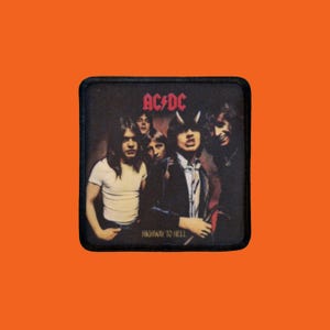 Peut inclure: Écusson carré représentant le groupe AC/DC avec le texte "AC/DC" en rouge et le titre de l'album "Highway to Hell". L'image montre les membres du groupe dans une ambiance sombre.