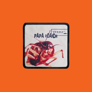 Peut inclure: Écusson carré à bordure noire avec une image détaillée d'un cafard. Les mots "PAPA ROACH" sont imprimés en blanc, avec "INFEST" au-dessus. Le fond est blanc cassé, sur un fond orange.