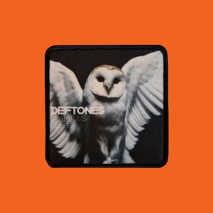 Peut inclure: Écusson carré avec une chouette blanche aux ailes déployées sur fond noir. Le texte "Deftones Diamond Eyes" est imprimé en blanc. L'écusson a une bordure noire et un fond orange.