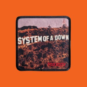 Könnte beinhalten: Quadratischer Aufnäher mit dem Text "SYSTEM OF A DOWN" in Weiß, vor einer sepiafarbenen Landschaft. Das Wort "TOXICITY" steht unten in Rot. Der Aufnäher hat einen schwarzen Rand.