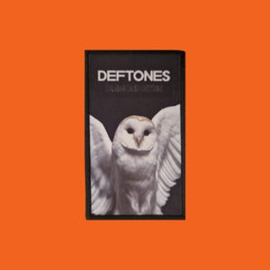 May include: Black patch with a white owl and outstretched wings. The text "DEFTONES" is above "DIAMOND EYES" in white. The patch has a black border, set against an orange background.