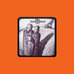 Könnte beinhalten: Ein quadratischer Aufnäher mit schwarzem Rand und einer Graustufenillustration. Das Bild zeigt drei Figuren, einen Weg und ein Gebäude. Der Text "THREE DAYS GRACE" ist oben aufgedruckt.