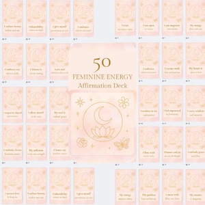 Può includere: Un mazzo di 50 carte di affermazione con un tema di energia femminile. Le carte sono rosa chiaro con illustrazioni dorate di lune, fiori e farfalle. Ogni carta ha un'affermazione diversa.