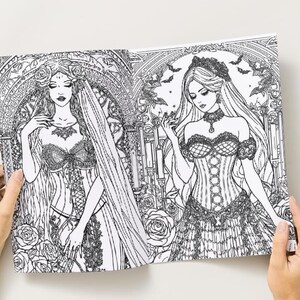 Puede incluir: Una p&aacute;gina doble de un libro para colorear en blanco y negro con dos ilustraciones de mujeres g&oacute;ticas con vestidos elaborados. Los dibujos est&aacute;n detallados con elementos florales y arquitect&oacute;nicos. El libro est&aacute; abierto por manos.