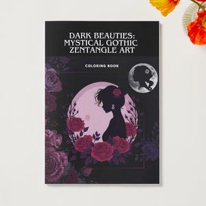 Puede incluir: Un libro para colorear titulado "Dark Beauties: Mystical Gothic Zentangle Art" presenta la silueta de una mujer rodeada de rosas. La portada es negra con un dise&ntilde;o circular en tonos rosa y morado. Tambi&eacute;n hay un peque&ntilde;o gr&aacute;fico de luna.