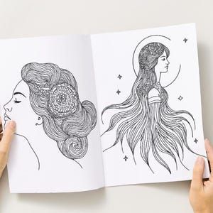 Peut inclure: Livre ouvert avec deux illustrations en noir et blanc de visages de femmes. L'une a des cheveux complexes et un motif circulaire. L'autre a de longs cheveux fluides, un halo et des &eacute;toiles. Le livre est tenu ouvert par des mains.