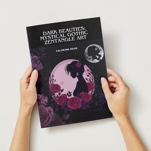 Puede incluir: Un libro para colorear titulado "Dark Beauties: Mystical Gothic Zentangle Art" es sostenido por manos sobre un fondo blanco. La portada presenta una silueta de mujer frente a una luna rosa, rodeada de rosas rojas. Una luna m&aacute;s peque&ntilde;a con una silueta est&aacute; en la esquina superior derecha.