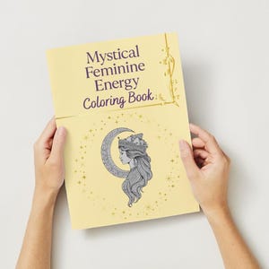 Peut inclure: Un livre de coloriage jaune intitul&eacute; &laquo; Mystical Feminine Energy Coloring Book &raquo; est ouvert. La couverture pr&eacute;sente une illustration du profil d'une femme dans un croissant de lune et des &eacute;toiles. Le livre a des accents dor&eacute;s d&eacute;coratifs.